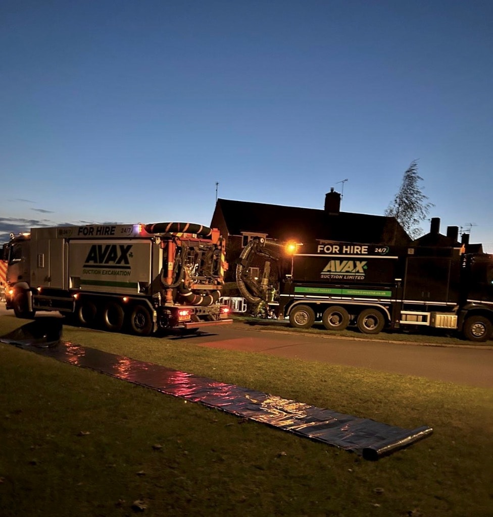 Two AVAX suction excavation units on site at night